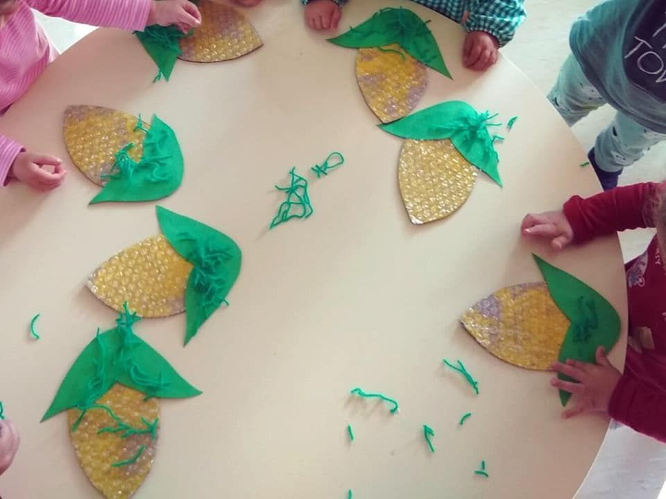 Un grupo de niños están sentados alrededor de una mesa con hojas sobre ella.