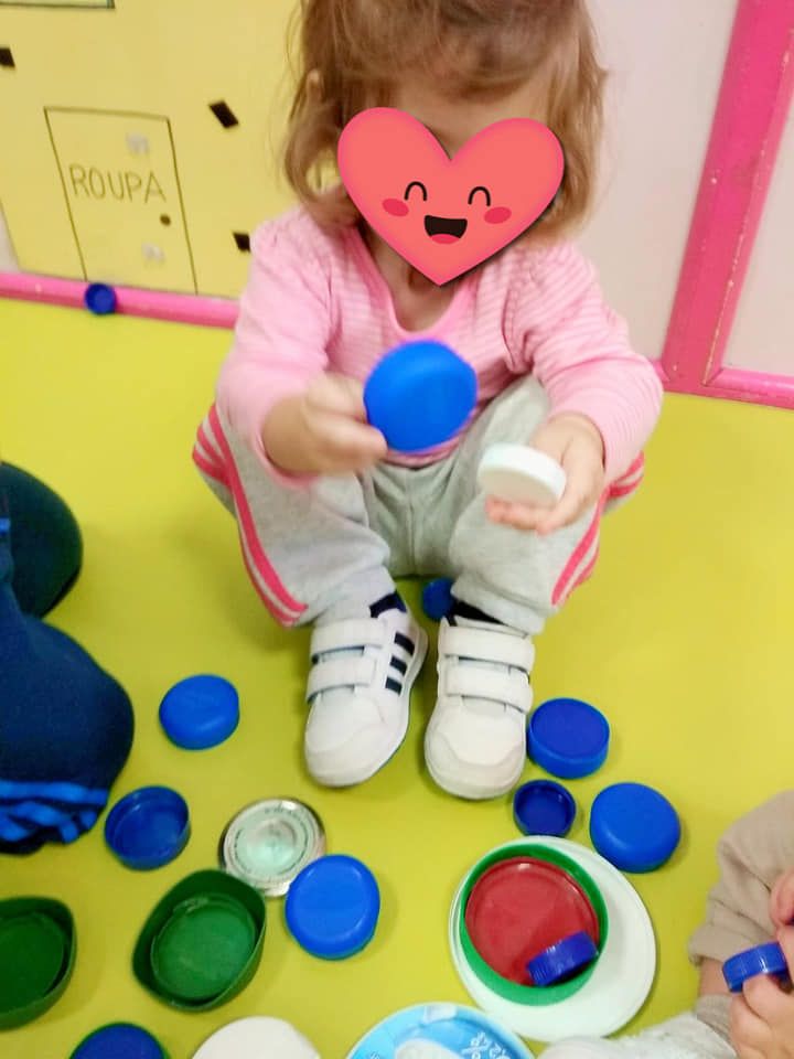 Una niña con un corazón en la cara está jugando con tapas de botellas.