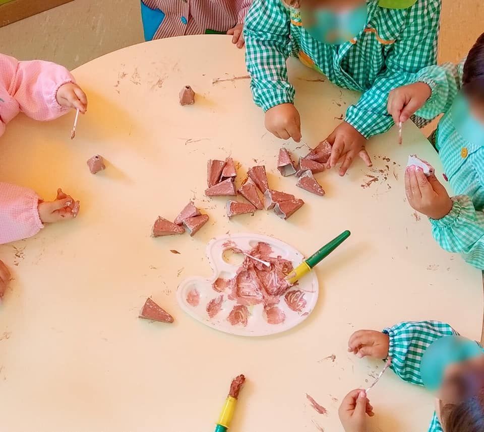 Un grupo de niños están sentados alrededor de una mesa jugando con arcilla.