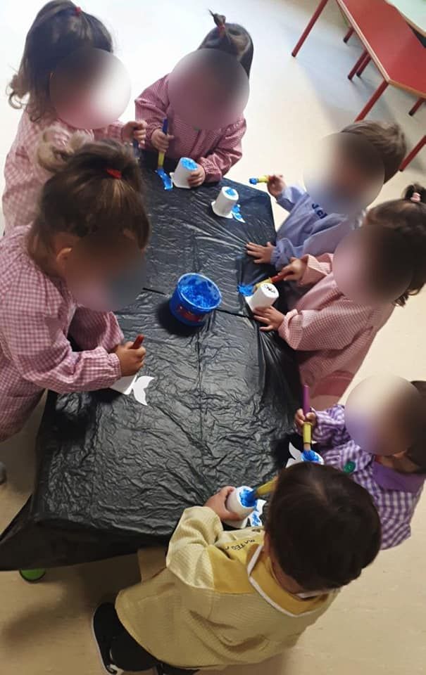 Un grupo de niños están sentados alrededor de una mesa haciendo manualidades.