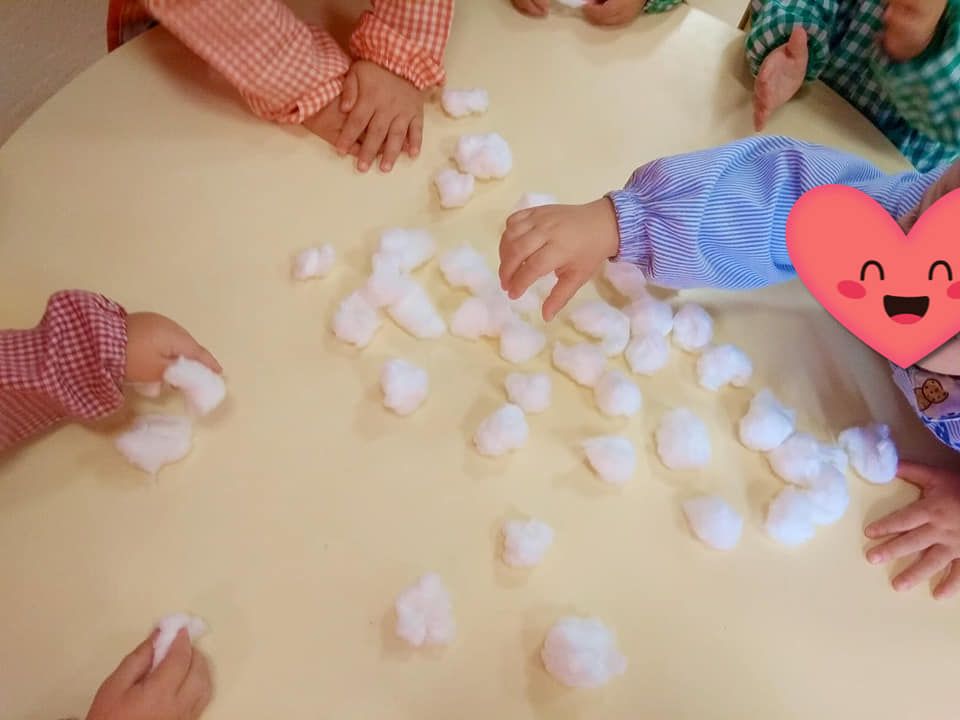 Un grupo de niños está jugando con bolas de algodón en una mesa.