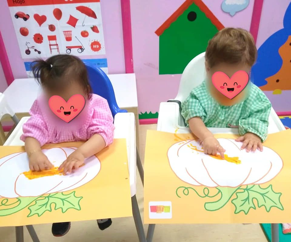 Dos niños están sentados en una mesa con una imagen de una calabaza en ella.