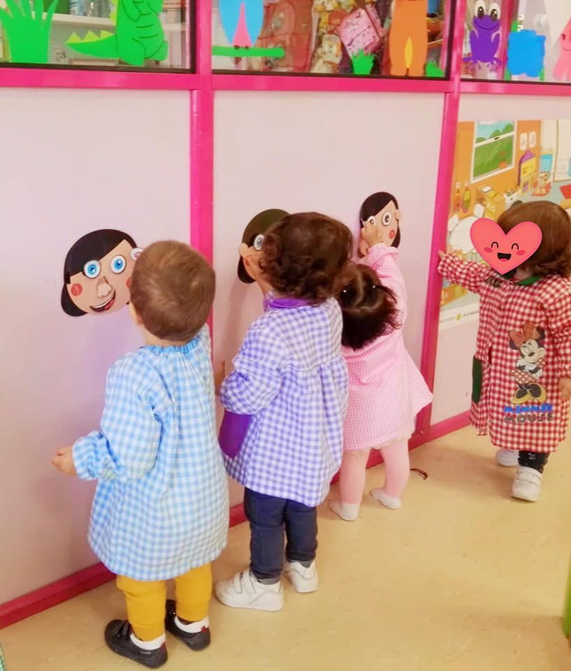 Un grupo de niños de pie frente a una pared rosa.
