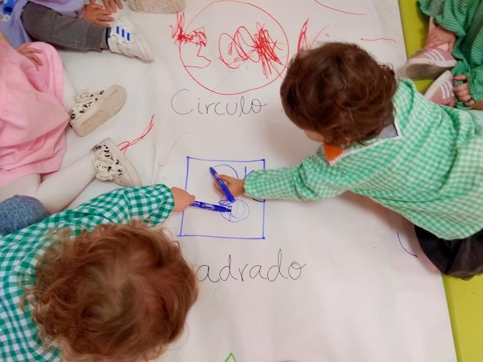 Un grupo de niños está dibujando en un trozo grande de papel que dice círculo.