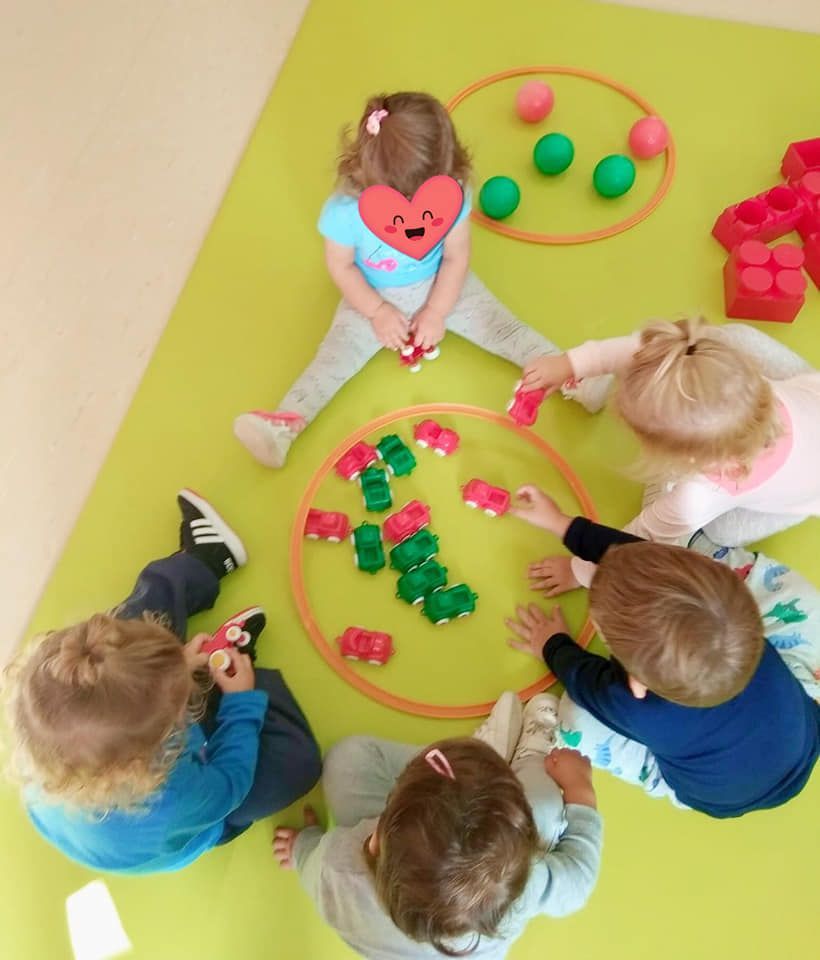 Un grupo de niños está jugando con juguetes sobre una alfombra verde.