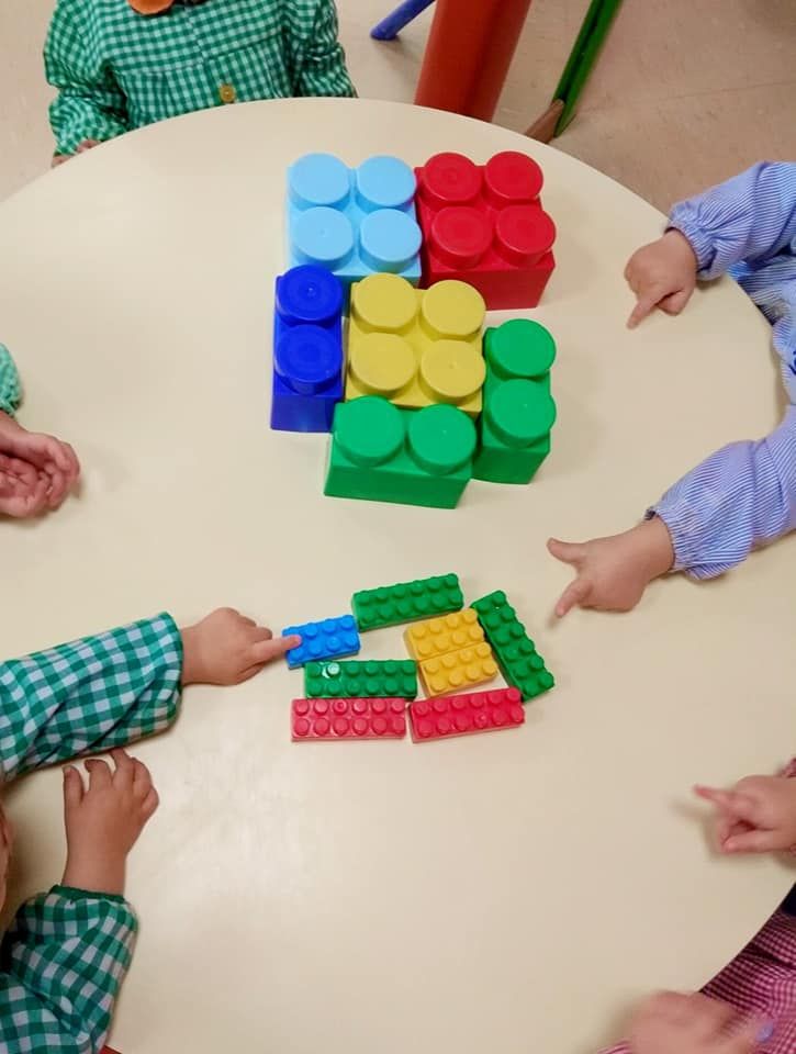 Un grupo de niños está jugando con bloques de Lego en una mesa.