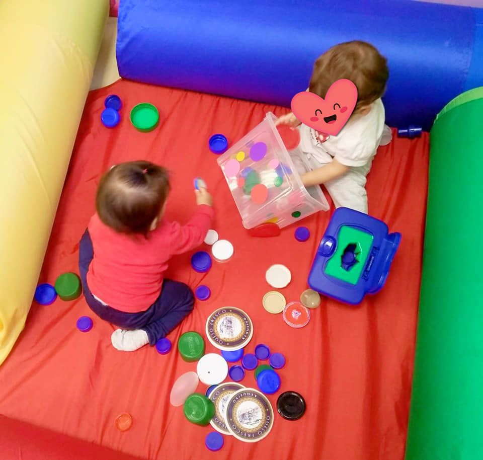 Dos niños juegan con juguetes en una cama roja.