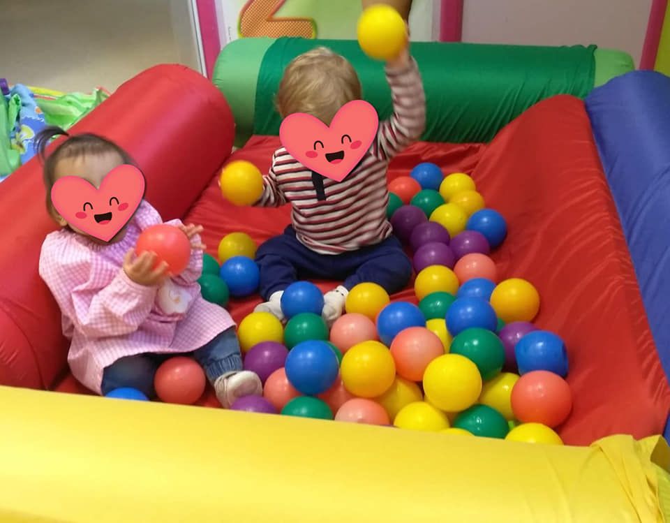Un niño y una niña están jugando en una piscina de pelotas.