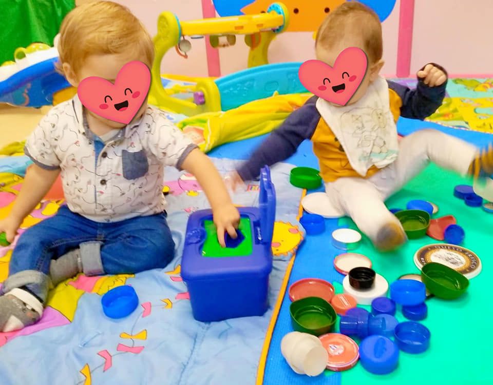 Dos bebés están sentados en el suelo jugando con juguetes.