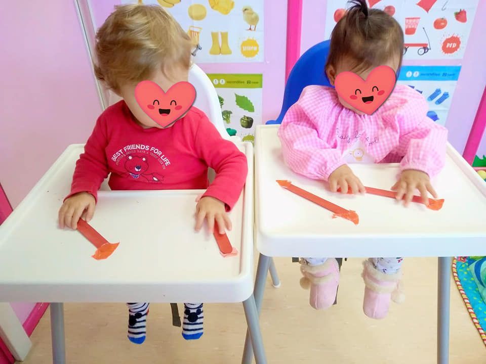 Un niño y una niña están sentados en sillas altas con corazones en sus caras.