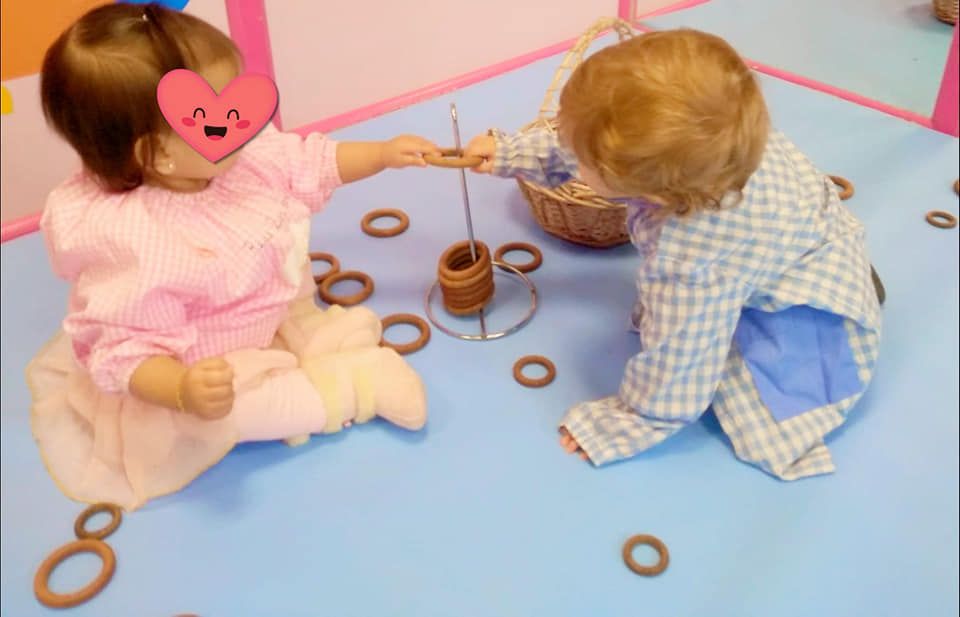 Un niño y una niña están jugando con anillos en el suelo.