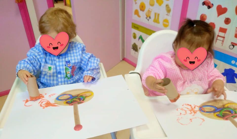 Dos niñas están sentadas en una mesa haciendo manualidades con rollos de papel higiénico.