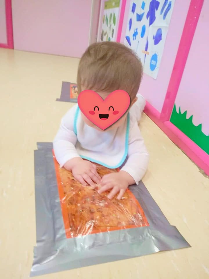 Un bebé con un corazón en la cara está jugando con cinta adhesiva.