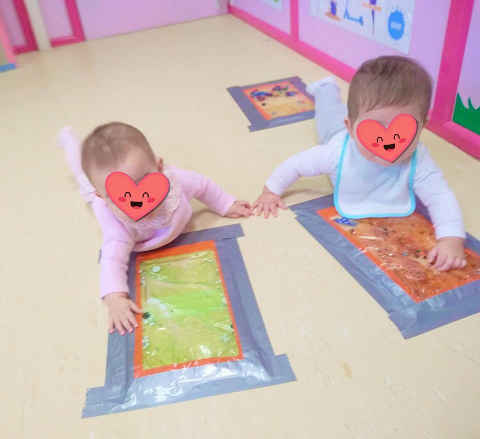 Dos bebés con corazones en sus caras están gateando por el suelo.