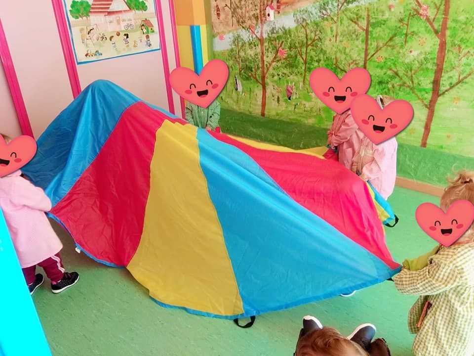 Un grupo de niños está jugando con un paracaídas colorido.