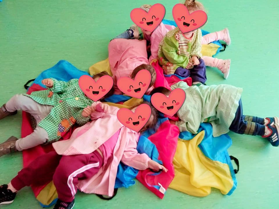 Un grupo de niños acostados en el suelo con corazones en sus caras.