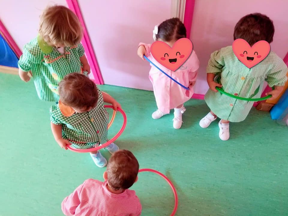 Un grupo de niños está jugando con aros de hula hula en una habitación.