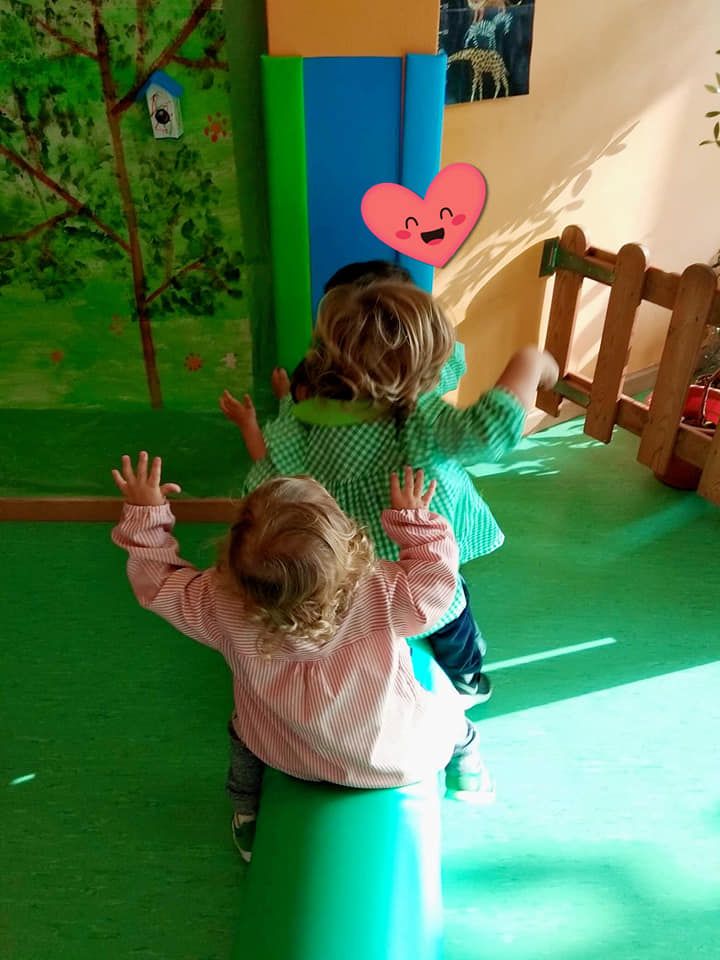 Dos niñas están sentadas en un cilindro verde en una habitación.