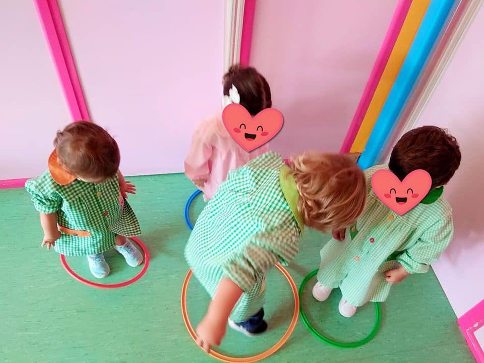 Un grupo de niños está jugando con aros de hula hula en una habitación.