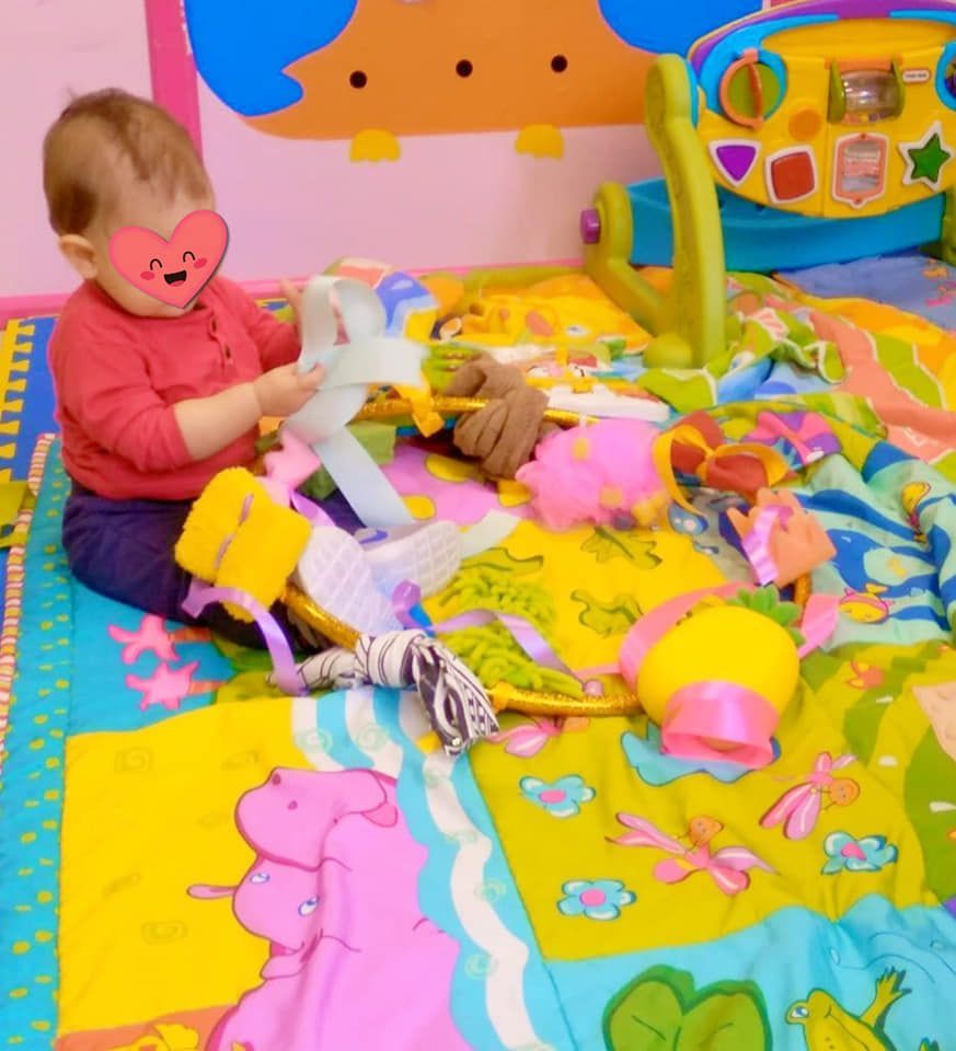 Un bebé que lleva una máscara está jugando con juguetes en el suelo.