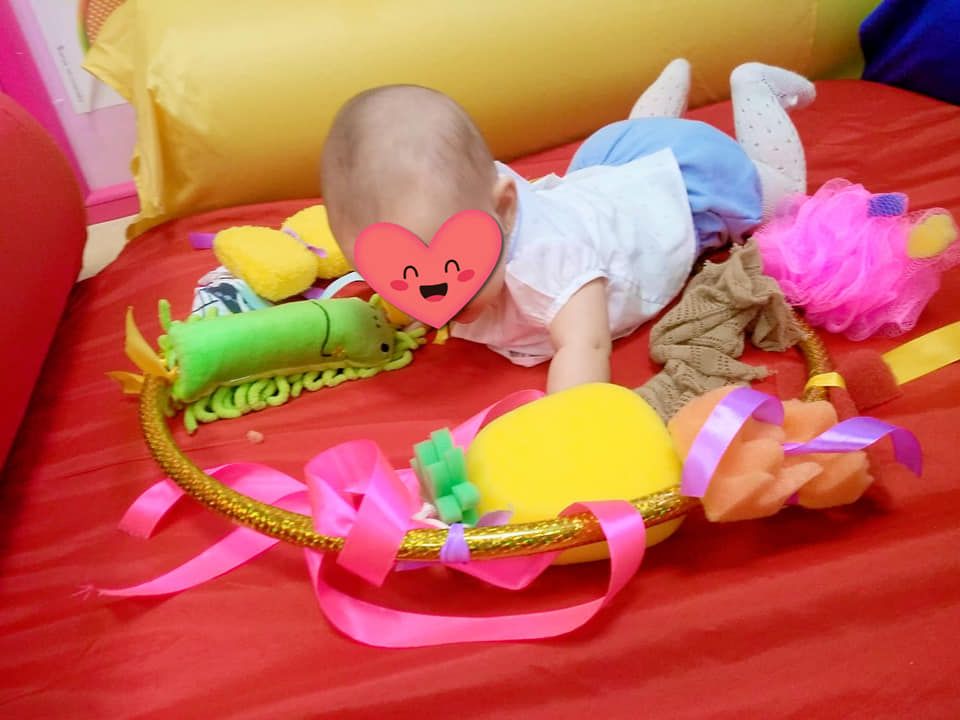 Un bebé está acostado boca abajo en un aro de animales de peluche.