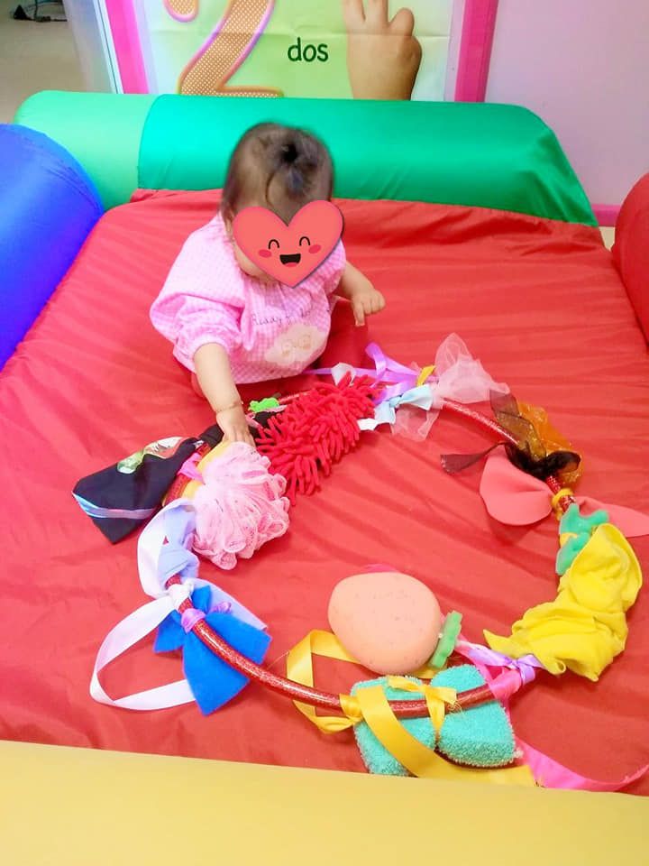 Un bebé con un corazón en la cara está jugando con juguetes en una cama.