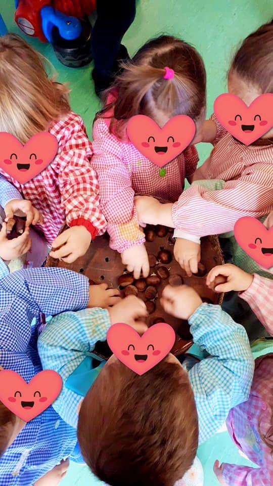 Un grupo de niños están sentados en círculo con corazones en sus caras.