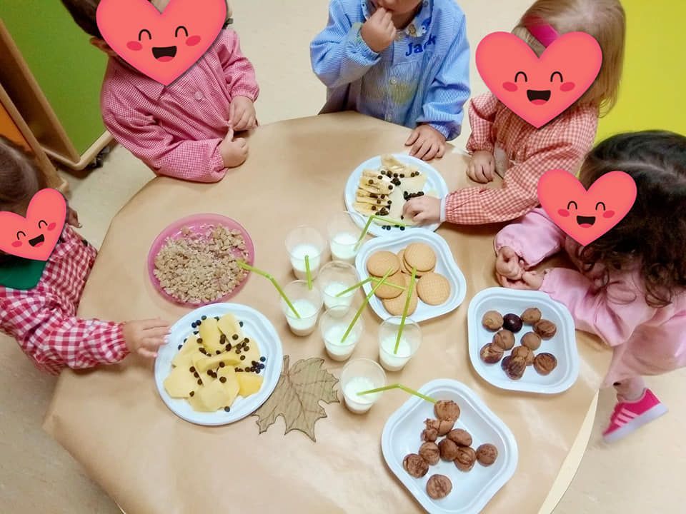 Un grupo de niños están sentados alrededor de una mesa con platos de comida.