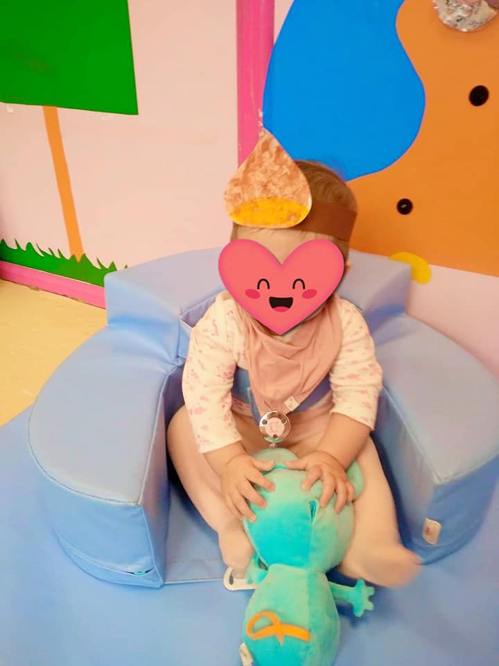 Un bebé con un corazón en la cara está jugando con un animal de peluche.