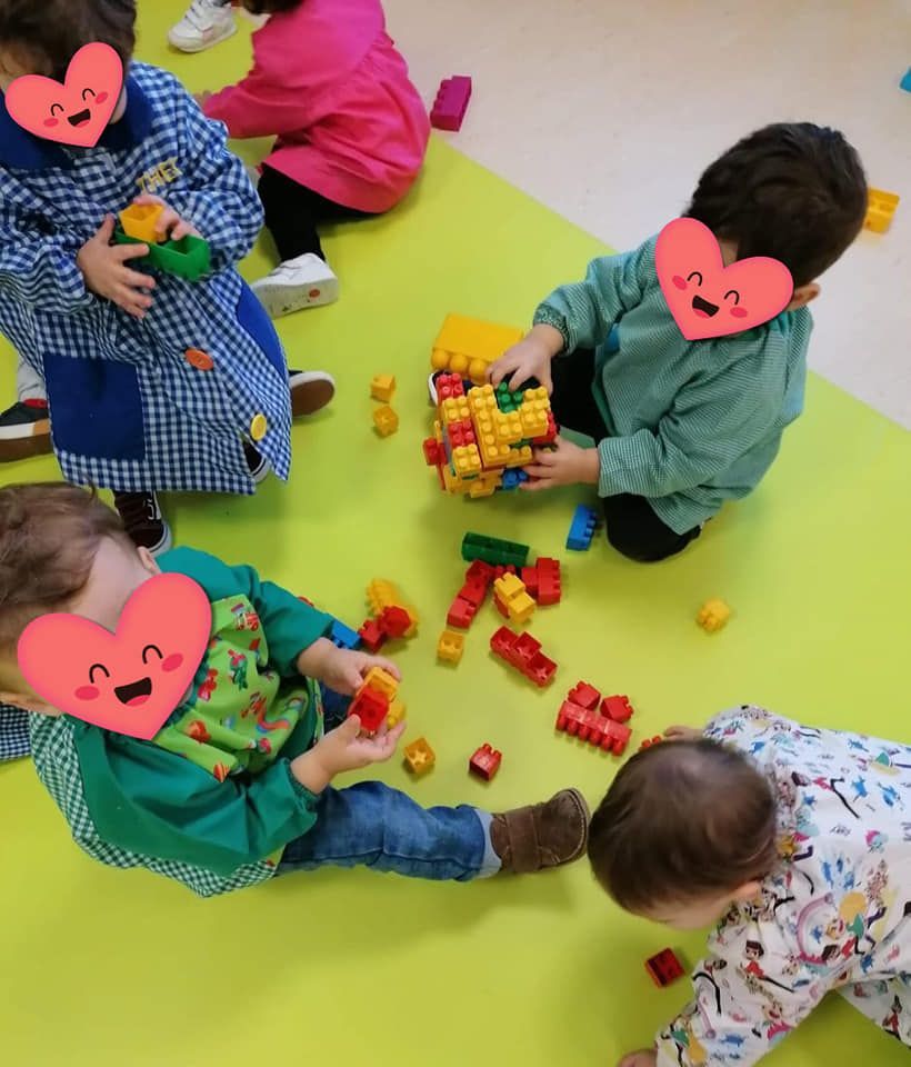 Un grupo de niños con corazones en sus caras están jugando con bloques de Lego.