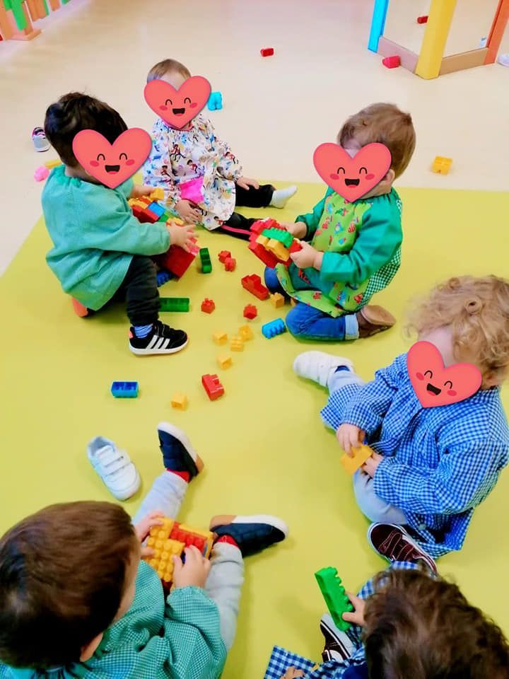 Un grupo de niños está sentado en el suelo jugando con bloques.