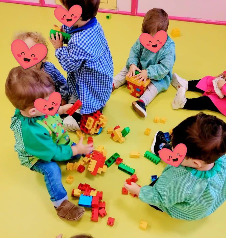 Un grupo de niños con corazones en sus caras están jugando con bloques de Lego.