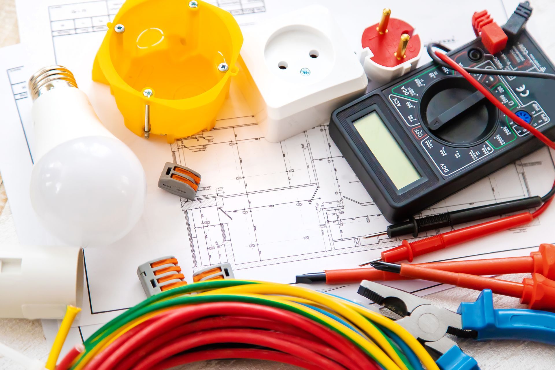 Outils électriques et multimètre sur un plan avec des fils et des casques de sécurité
