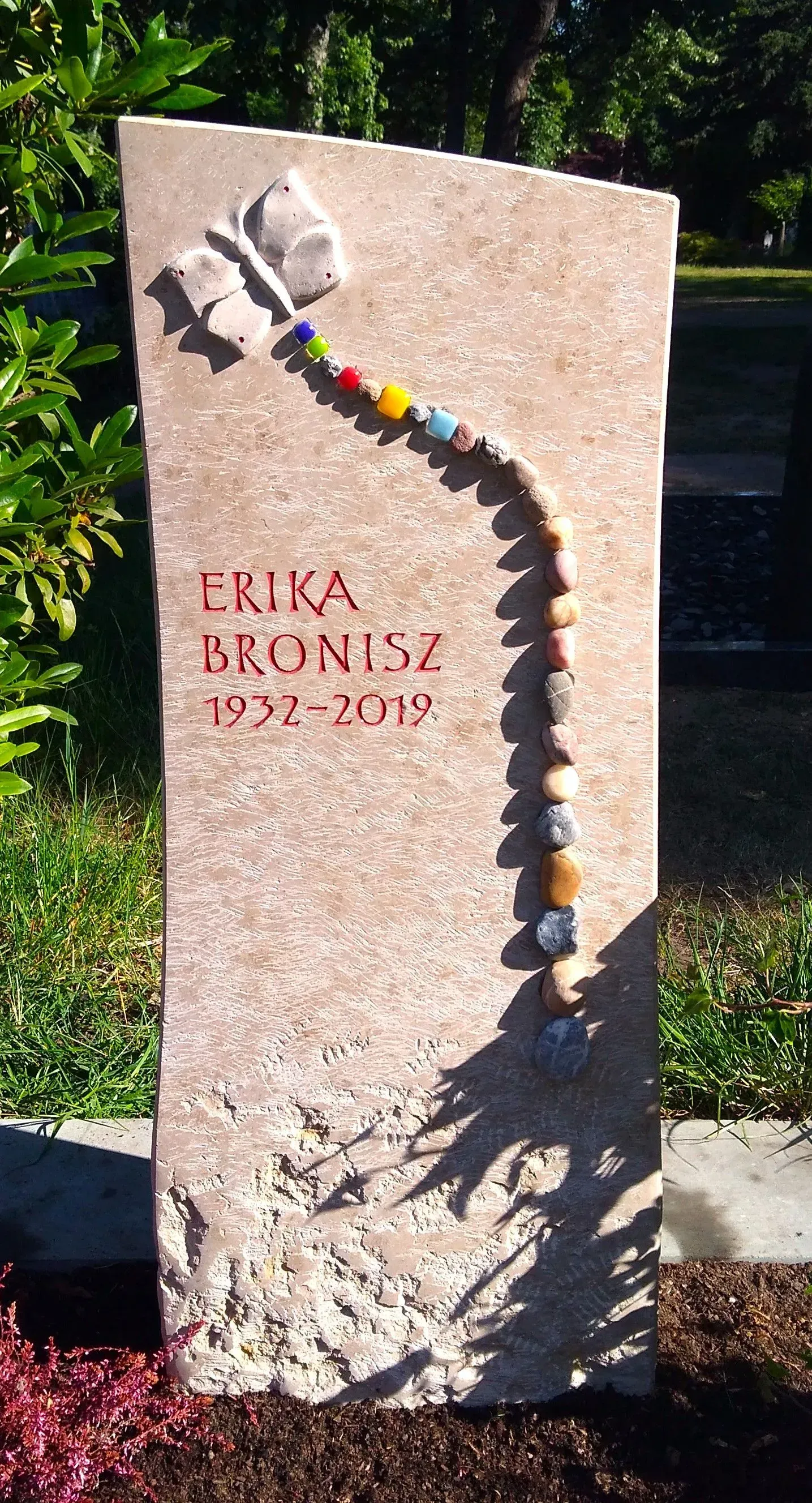 Heller Naturstein mit Schmetterlings-Relief und bunter Perlen-Applikation.