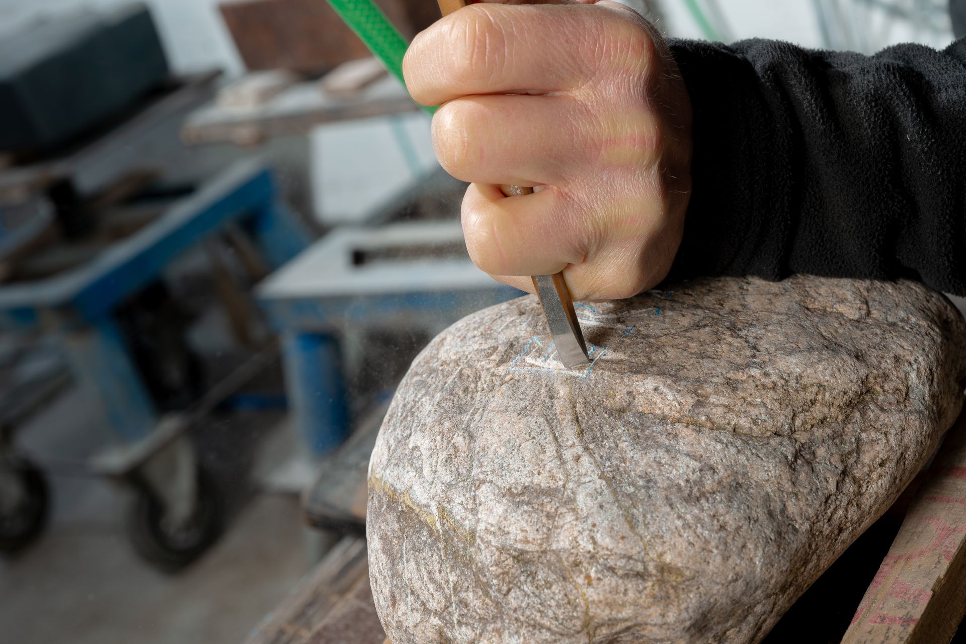 Nahaufnahme: Hand führt einen Meißel bei der Steinbearbeitung.
