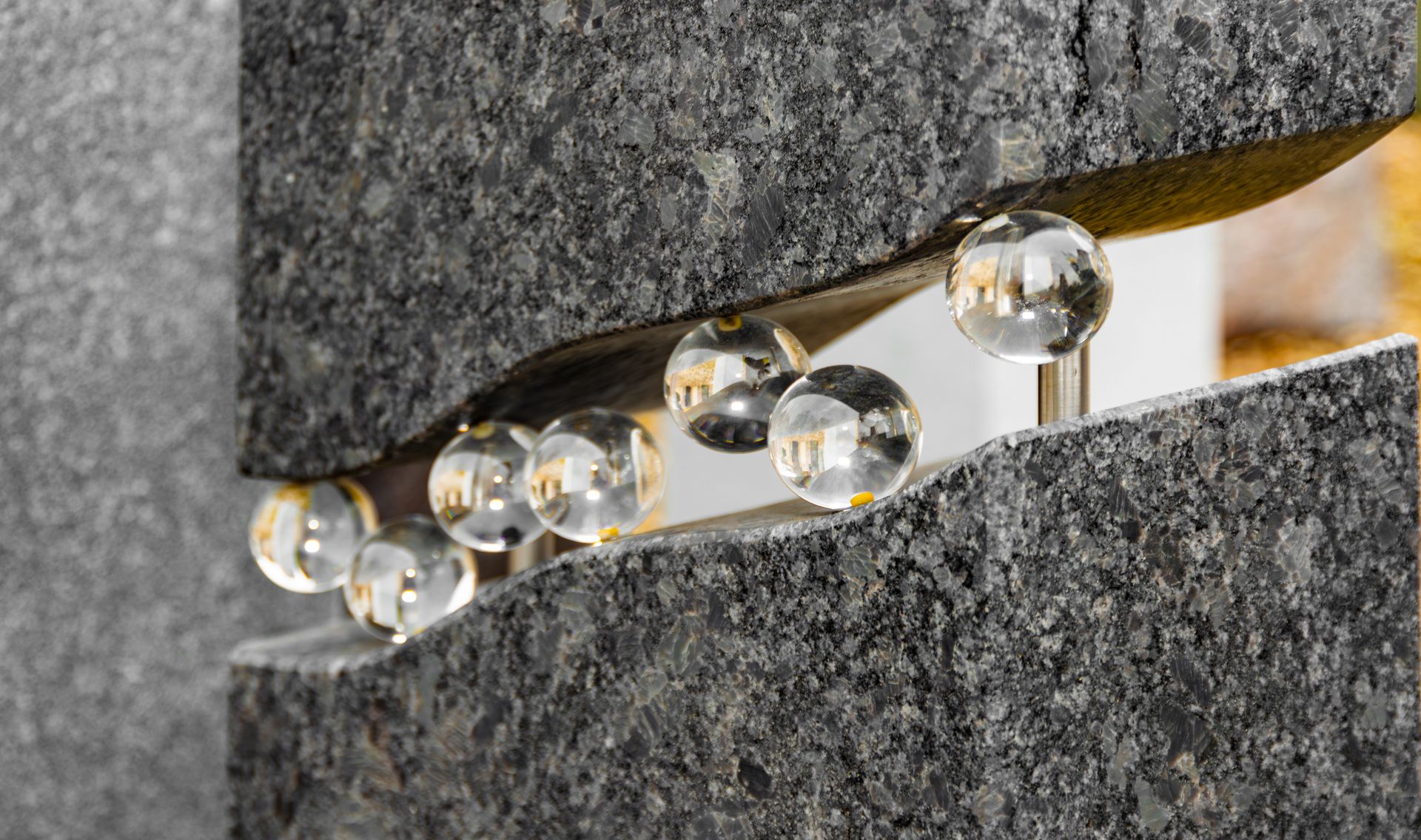 Nahaufnahme eines Grabsteins mit Glaskugeln in einer geschwungenen Steinspalte.