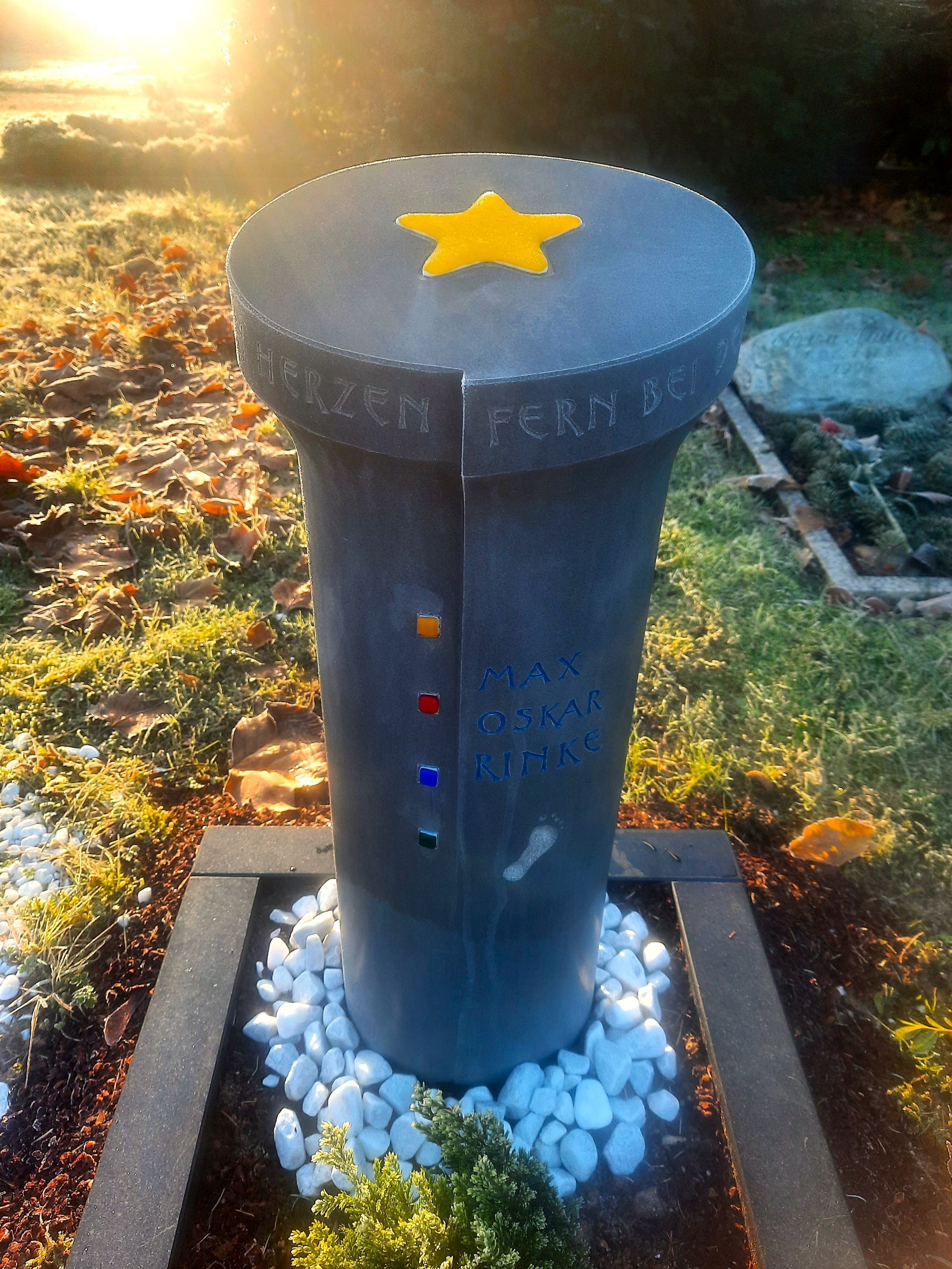 Rundes Kindergrabmal mit goldfarbenem Stern im Sonnenlicht