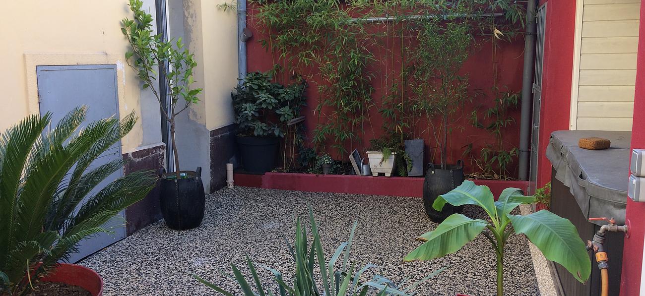 Petite cour en rouge avec du gravier et des plantes