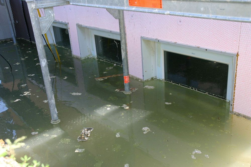 Die Gebäudeaußenfassade ist von trübem Wasser überflutet; die Fenster stehen teilweise unter Wasser.