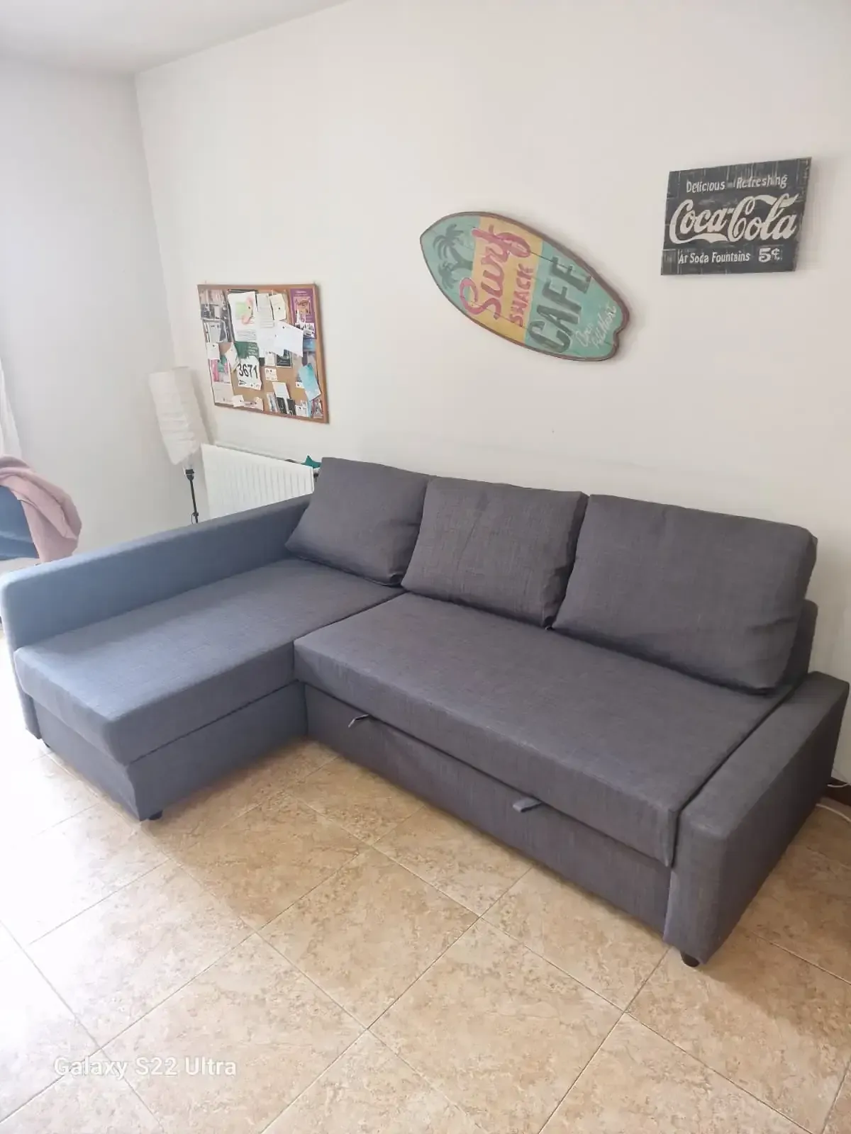 Sofá seccional gris con chaise longue en una sala de estar; decoración en la pared.