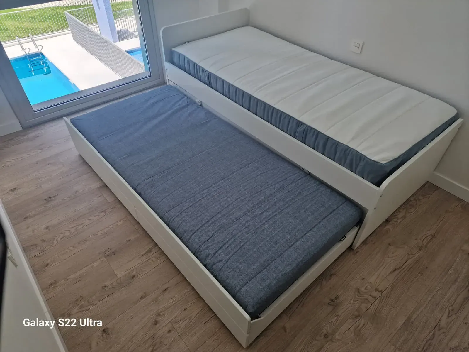 Dos camas individuales blancas, una debajo de la otra. 