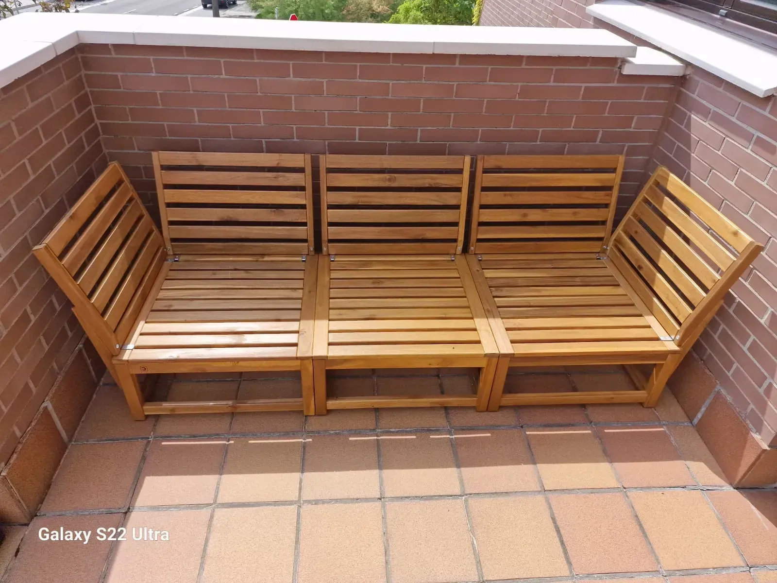 Asientos seccionales de madera para exterior en un patio de ladrillo.