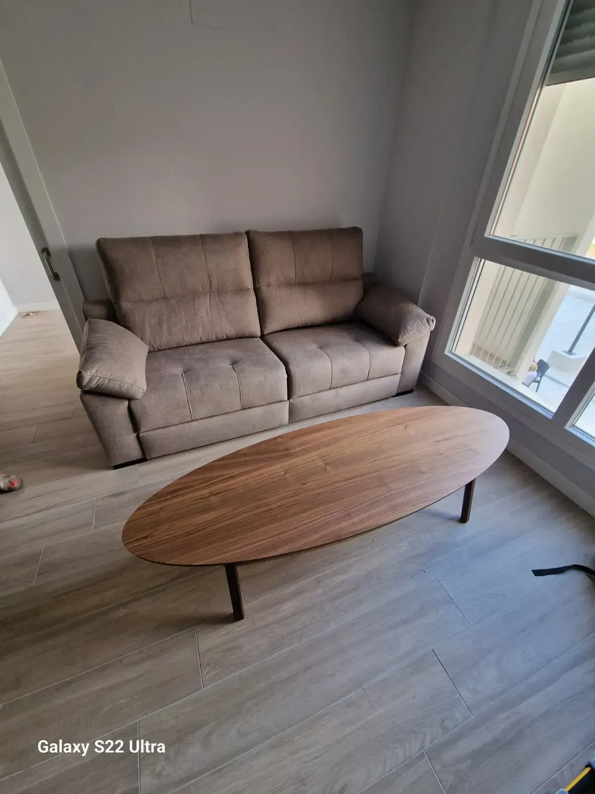 Sala de estar con sofá marrón y mesa de centro ovalada de madera.