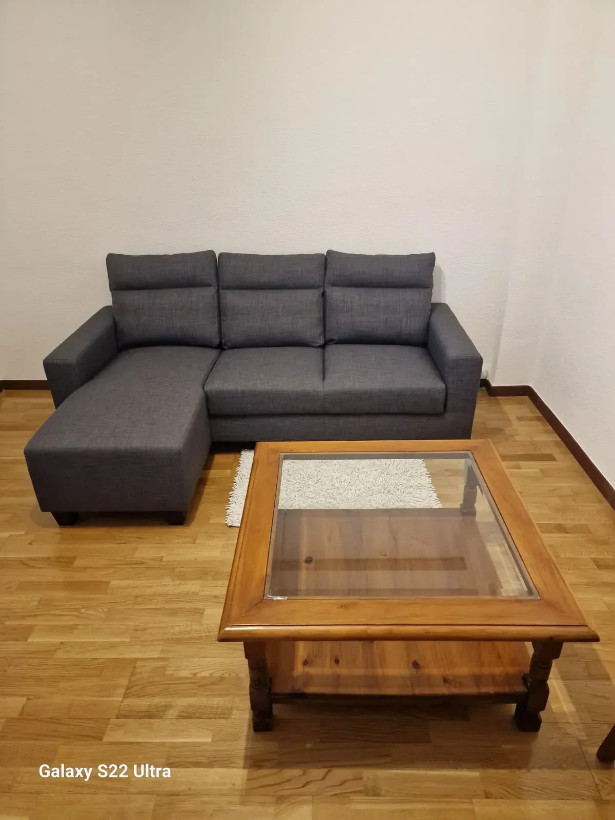 Sofá seccional gris y mesa de centro de madera en una habitación con pisos de madera.