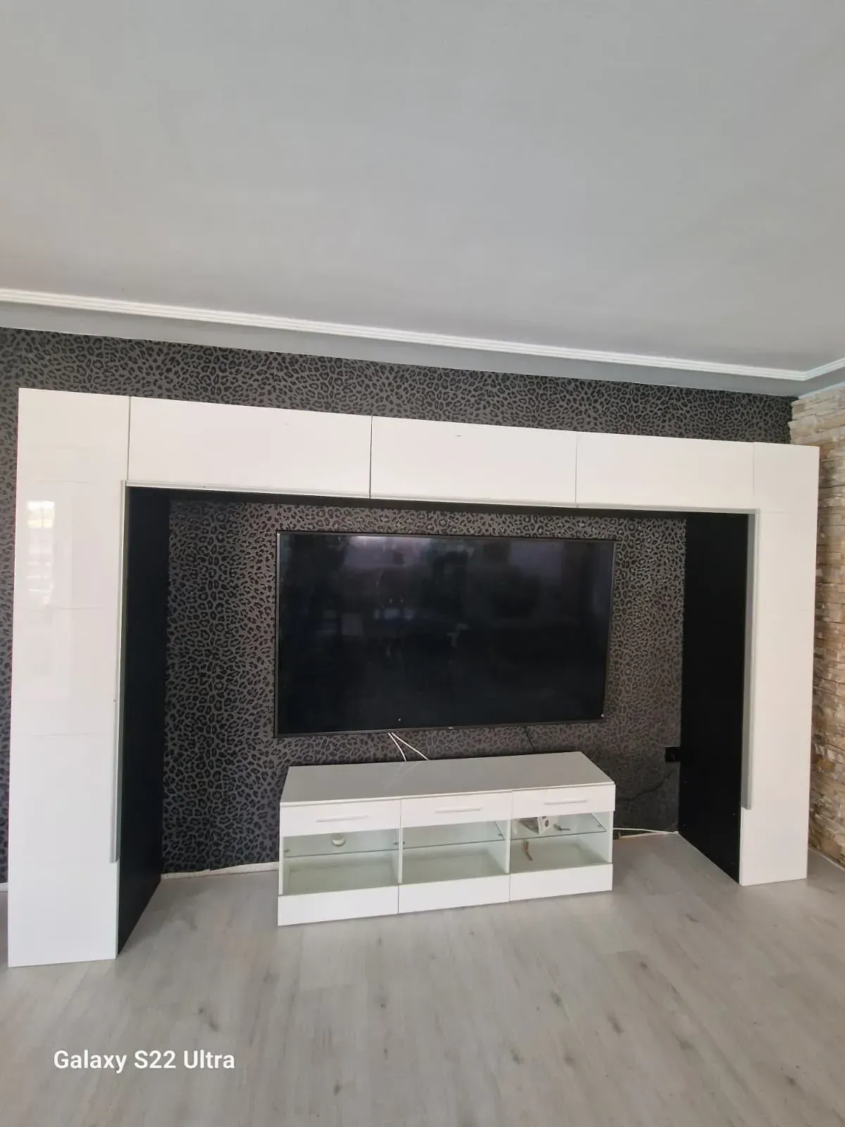 Centro de entretenimiento en la sala de estar con mueble blanco, televisor negro y marco blanco brillante.