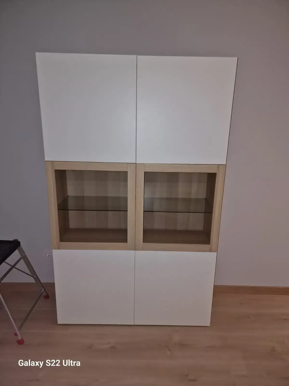 Vitrina en tonos blanco y madera con sección de exhibición con frente de vidrio; ambiente interior con piso de madera.