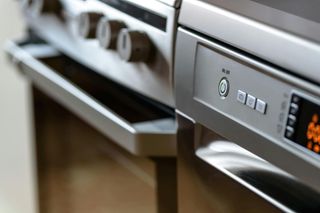 Horno y lavavajillas con acabado plateado, primer plano de controles y manijas de las puertas.