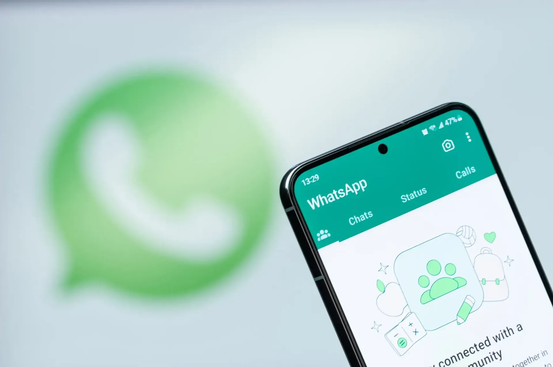 Teléfono inteligente que muestra la aplicación WhatsApp con el logotipo de la aplicación en el fondo.