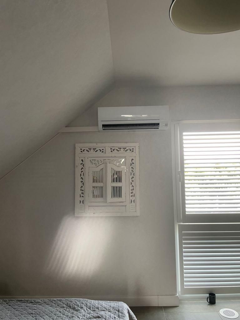 Ein Schlafzimmer mit einem Fenster und einem Spiegel an der Wand.