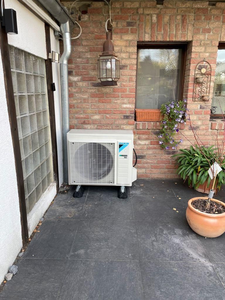 Eine weiße Klimaanlage steht außerhalb eines Backsteingebäudes